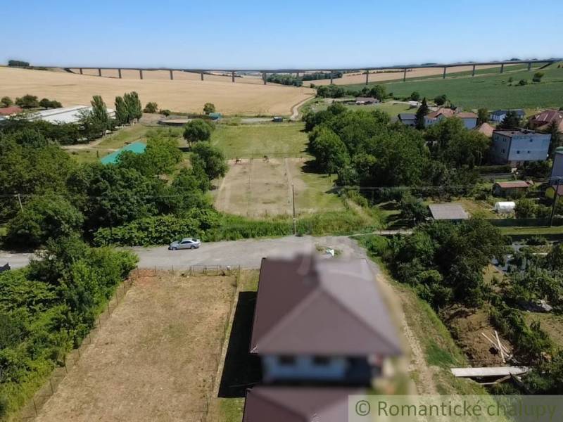 A vendéglátó vidéki lakótelkeket mutat be, háttérben egy híd panorámájával.