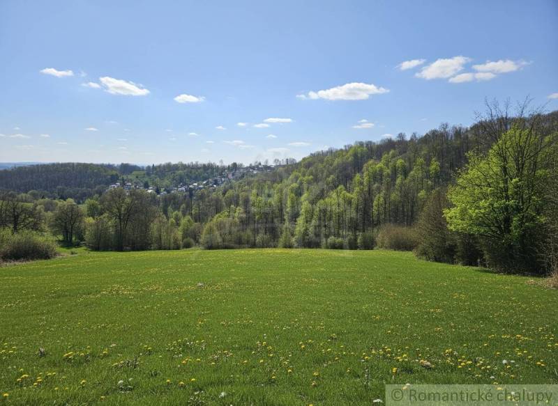 Tavaszi táj Krupina környékén, lakóterületek, zöld rétek és erdők a horizonton.