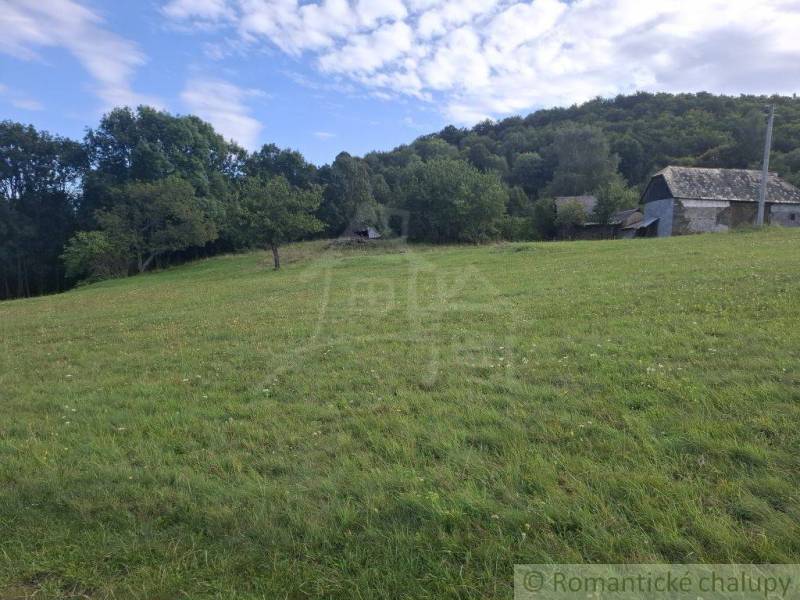 Rétek és épületek a Felsőtisovníkban, erdővel körülvéve.