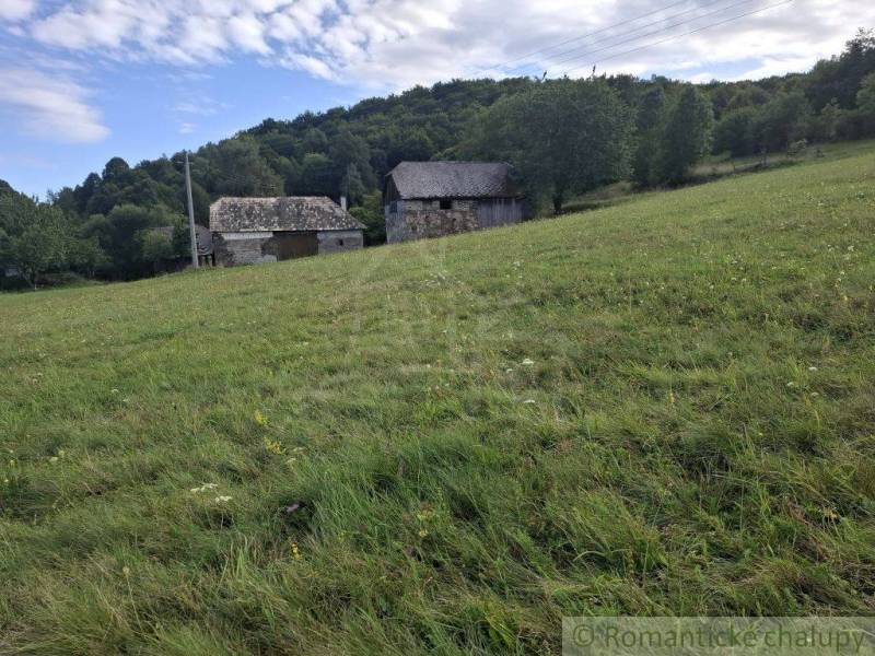 Füves domboldal épületekkel a háttérben, természettel körülvéve Felsőtisztviselőn, ideális lakóterületnek.