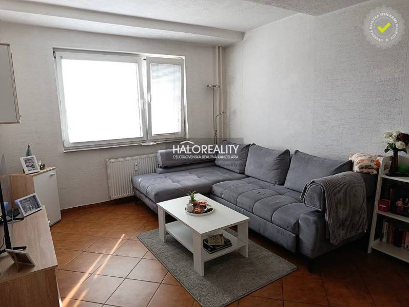 Nappali egy kétszobás lakásban sarokkanapéval és dohányzóasztallal fa dekor padlón.