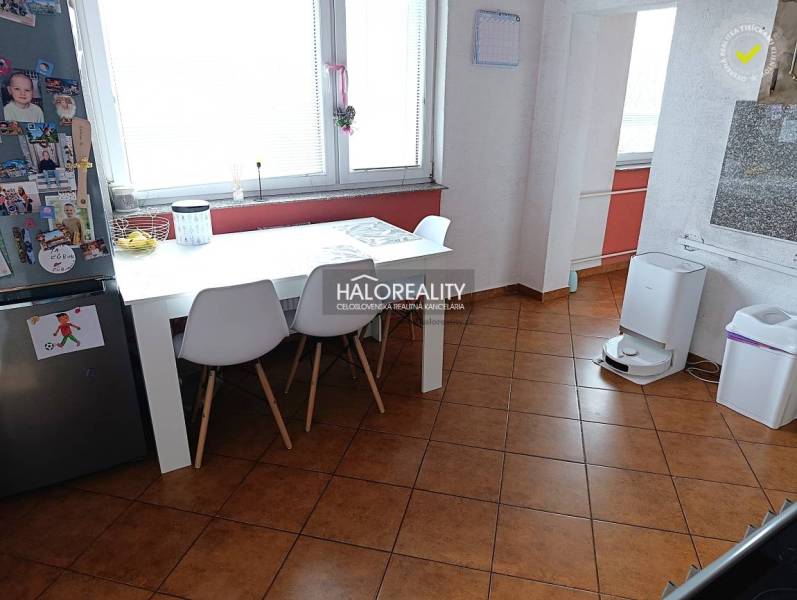 Ebédlő egy kétszobás lakásban fehér asztallal és barna padlóval.