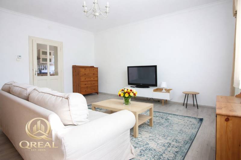 Nappali televízióval, kanapéval és dohányzóasztallal egy egyszobás lakásban.