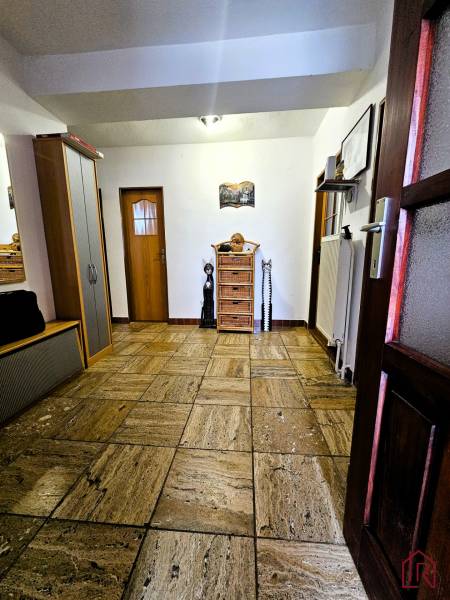 Folyosó kerámia burkolattal, faajtókkal és szekrénnyel a családi házban.