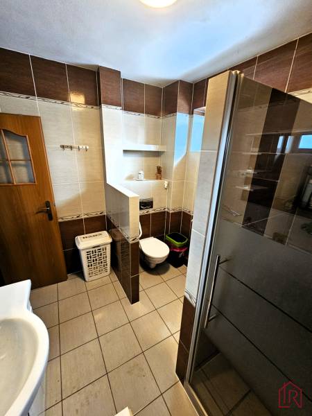 Fürdőszoba családi házban csempével, zuhanyzóval és WC-vel.