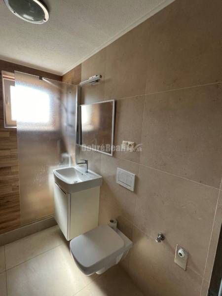 Fürdőszoba egy kétszobás lakásban mosdóval, zuhanyzóval és WC-vel.