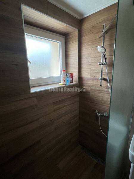 Zuhanykabin egy kétszobás lakásban fa dekor csempével és ablakkal.