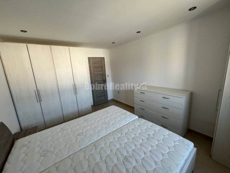 Hálószoba egy kétszobás lakásban fehér bútorokkal és fa dekorációjú padlóval.