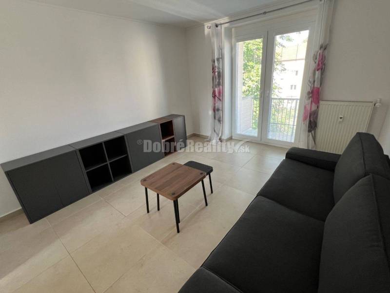 Nappali egy kétszobás lakásban fekete kanapéval és asztallal.