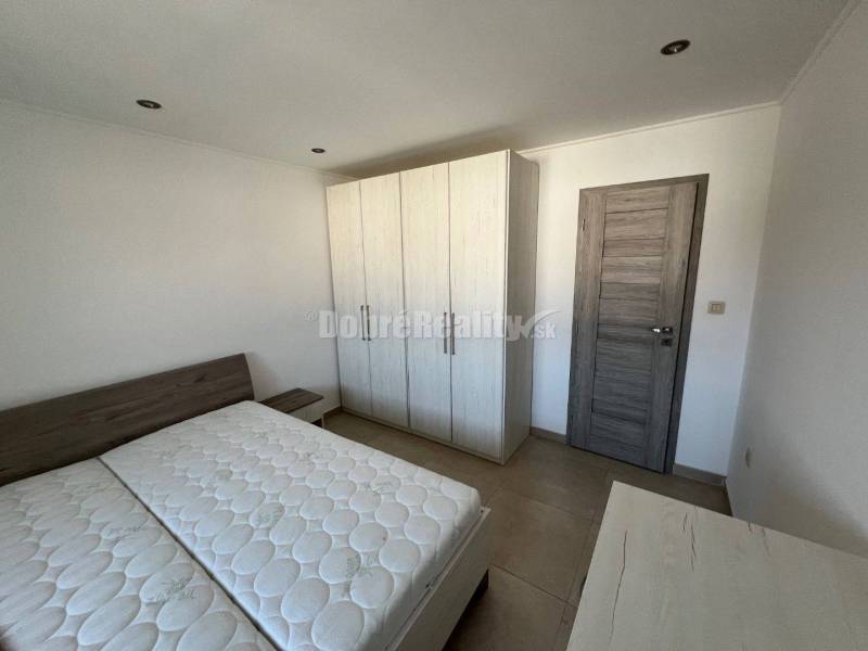 Hálószoba egy kétszobás lakásban ággyal és szekrénnyel, fa dekoros padlóval.
