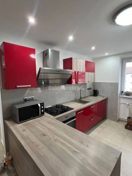 Konyha egy kétszobás lakásban beépített készülékekkel és fa mintázatú padlóval.