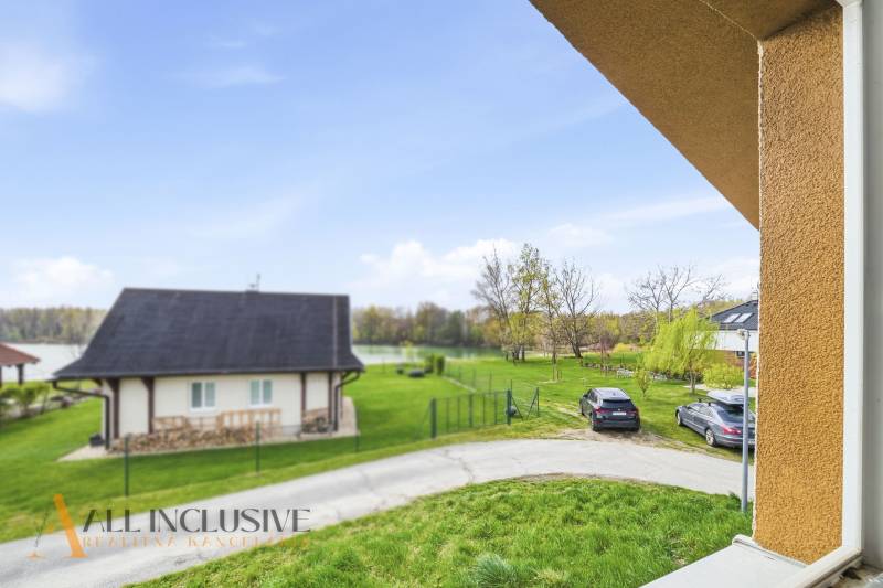 Házikó Vojkán, a tó mellett, autóval és zöld gyepes udvarral.