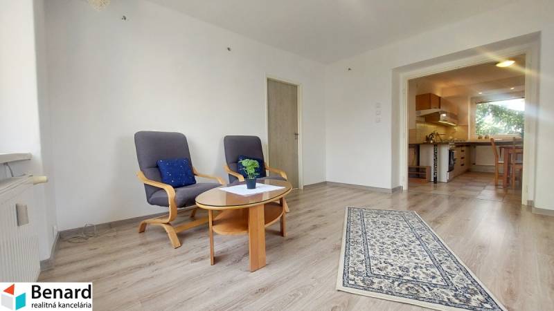 Nappali egy kétszobás lakásban fa mintázatú padlóval és kényelmes fotelekkel.