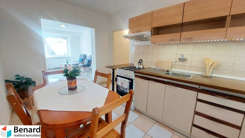 Konyha egy kétszobás lakásban ülősarokkal, világos padlóval és étkezőasztallal.