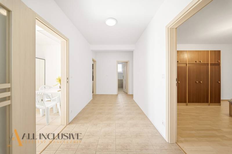 Folyosó egy családi házban, szobák ajtóival és padlócsempével.