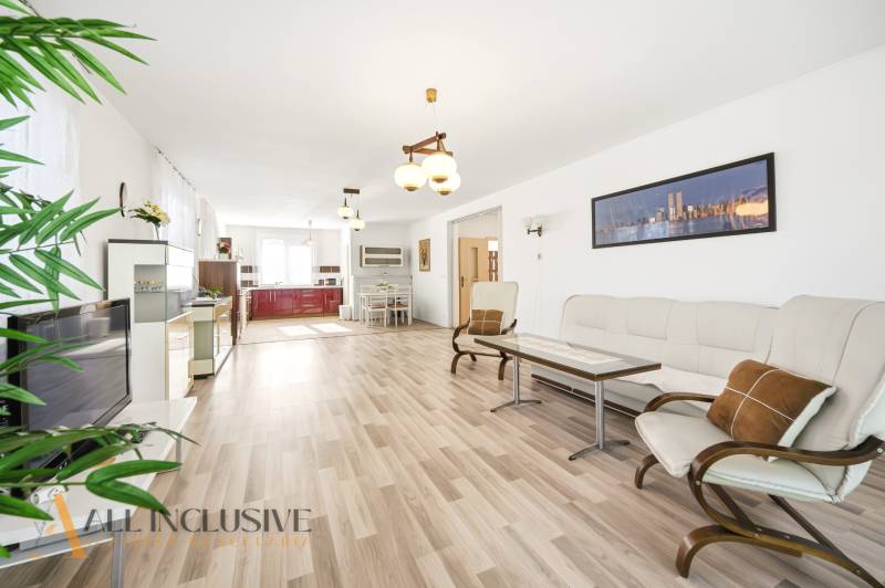 Nappali egy családi házban, fa dekorációjú padlóval és világos bútorokkal.