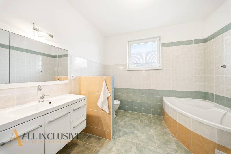 Fürdőszoba káddal, tükörrel és tárolóhellyel egy családi házban.