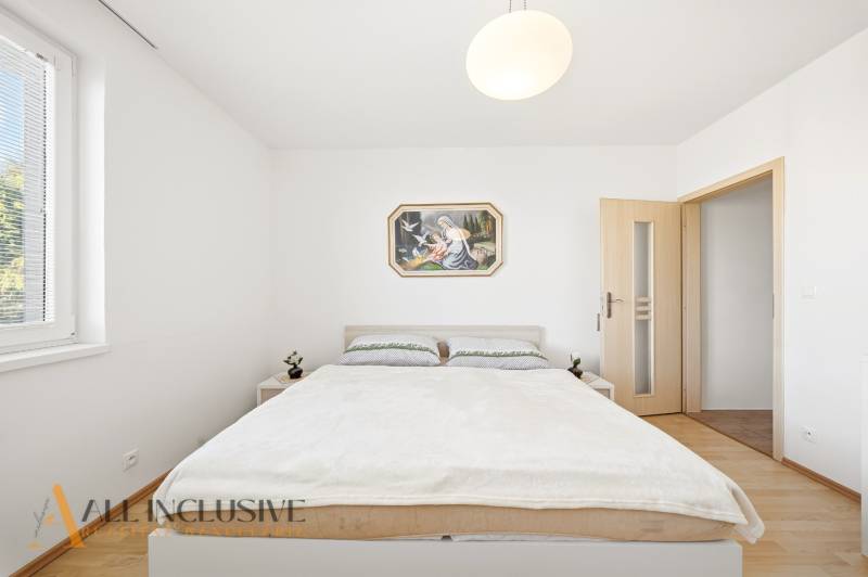 Hálószoba családi házban egyszerű bútorokkal és fa dekoros padlóval.