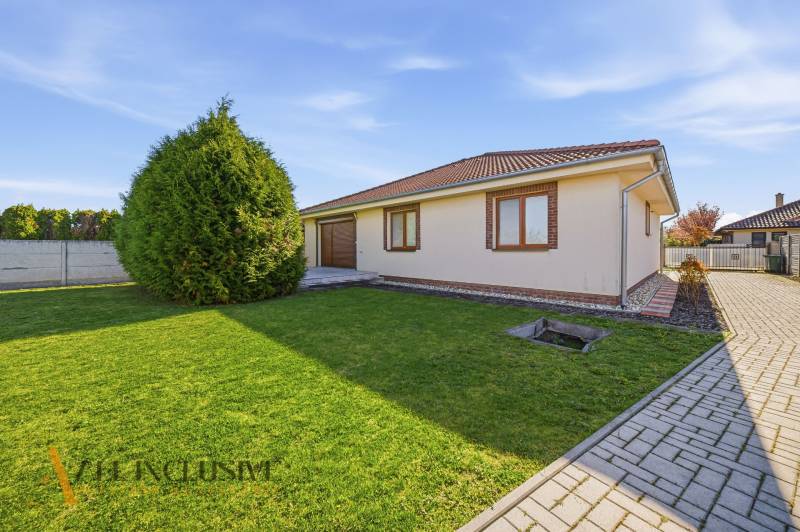 Családi ház Kútnikokban gyeppel, fákkal és térkövekkel.