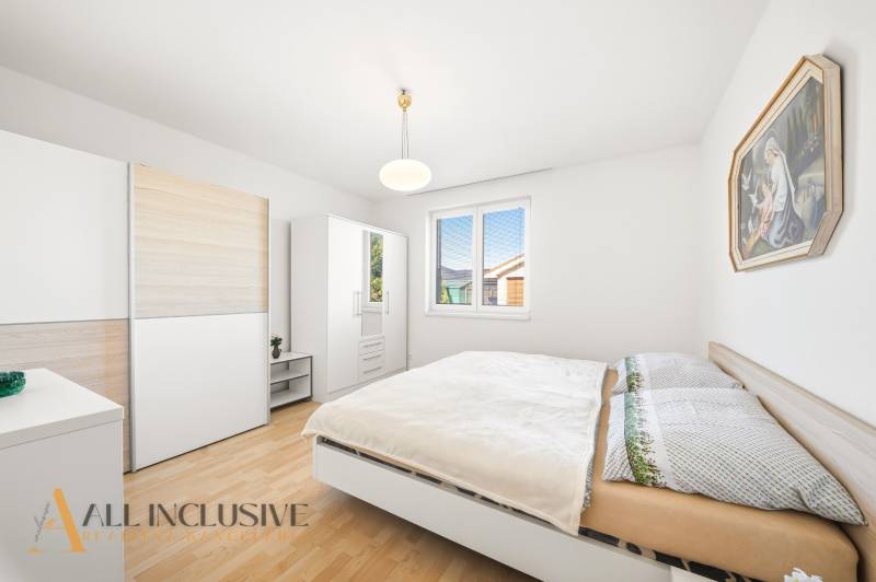 Hálószoba családi házban fa mintázatú padlóval, fehér bútorokkal és képpel.