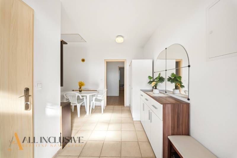 Családi ház belső tere fehér asztallal és székekkel, nagy tükörrel a falon.