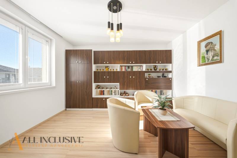 Nappali egy családi házban, fa dekorációjú padlóval és kényelmes ülőgarnitúrával.