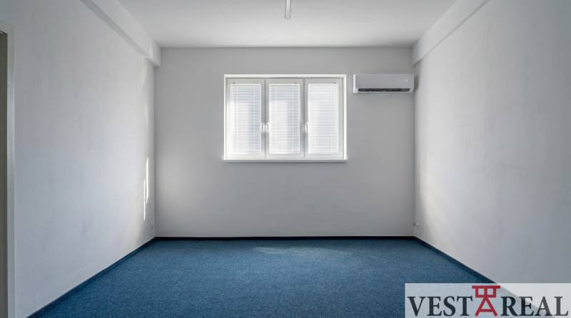 Irodák kék szőnyeggel, fehér falakkal és légkondicionálással.