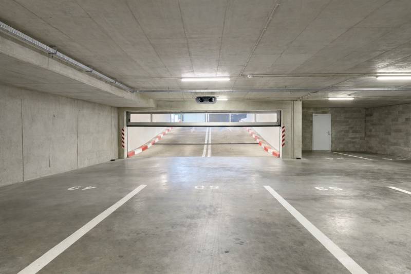 Parkolóhelyek garázsokban rámpával és fehér jelöléssel.