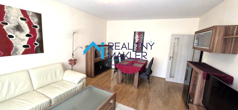 Nappali kanapéval, étkezőasztallal és fa dekorációjú padlóval egy háromszobás lakásban.