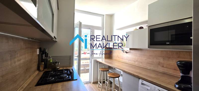 Konyha egy háromszobás lakásban bárpulttal, mikrohullámú sütővel és főzőlappal.