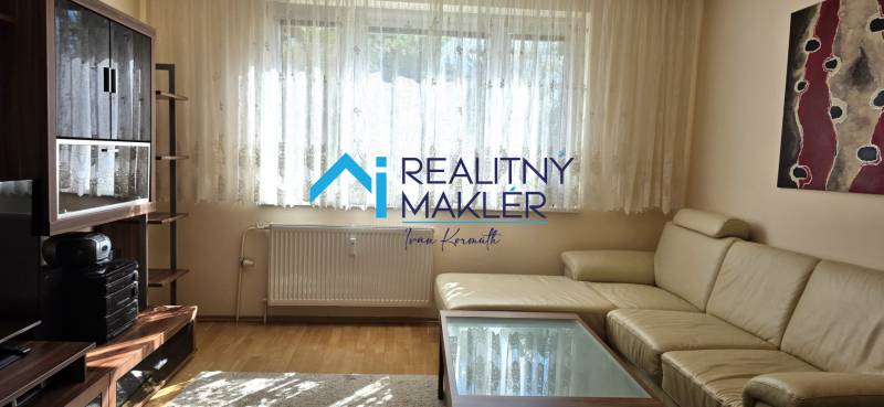 Nappali egy háromszobás lakásban fa dekoros padlóval és bőr kanapéval.