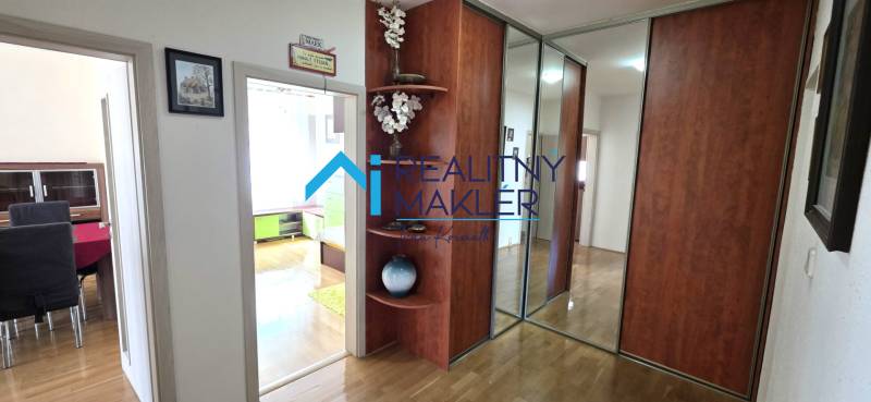 Folyosó egy 3 szobás lakásban fa dekor padlóval és beépített szekrénnyel.