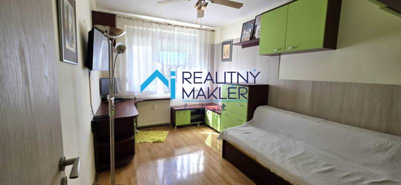 Nappali kanapéval, polcokkal és asztallal egy háromszobás lakásban, fa dekorációjú padlóval.