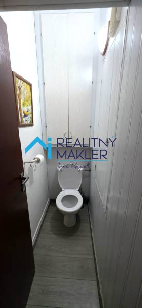 WC fa hatású padlóval egy háromszobás lakásban.