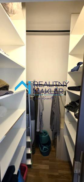 Beépített polcokkal és fa dekorációjú padlóval rendelkező gardrób egy háromszobás lakásban.