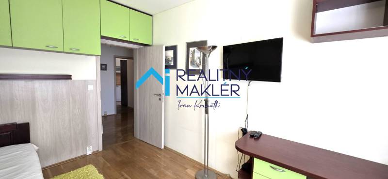 3 szobás lakás belső tere fa dekor padlóval, zöld tárolószekrényekkel.