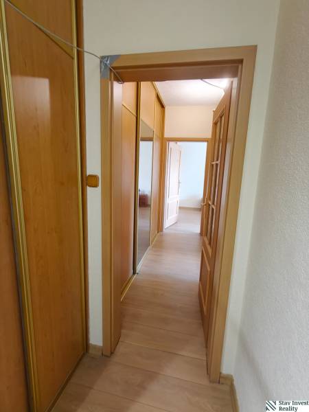Folyosó egy 3 szobás lakásban fa dekoros padlóval és tükrös szekrénnyel.
