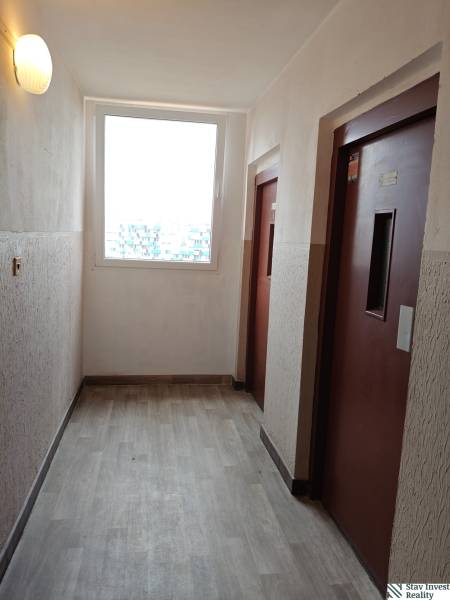 Liftfolyosó és fa mintázatú padló egy háromszobás lakásban.