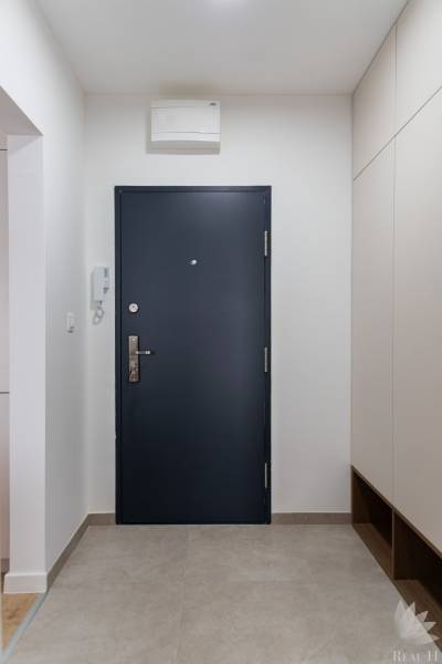 Előszoba egy háromszobás lakásban sötét ajtókkal és csempével.