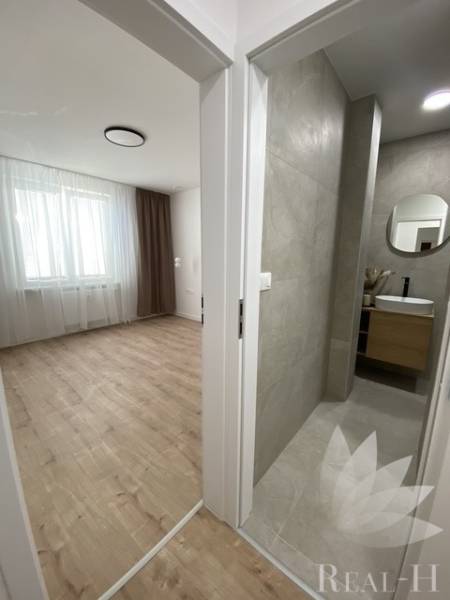 Szoba fa dekorációjú padlóval a fürdőszoba mellett egy kétszobás lakásban.