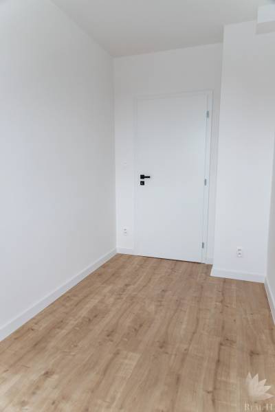 Szoba egy háromszobás lakásban fehér falakkal és fa dekorációjú padlóval.