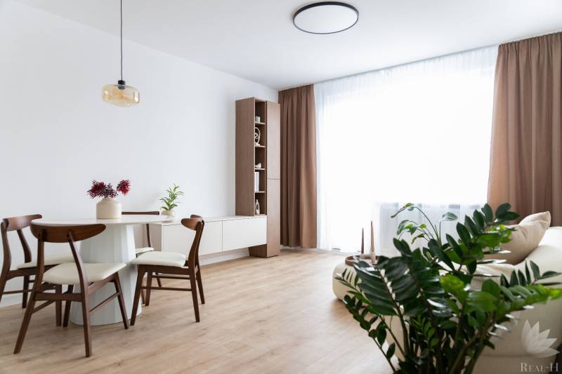 Nappali étkezőasztallal és fa dekorációjú padlóval egy háromszobás lakásban.