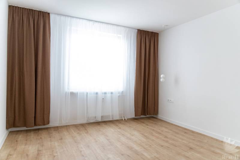 Szoba egy háromszobás lakásban barna függönyökkel és fa dekorációjú padlóval.