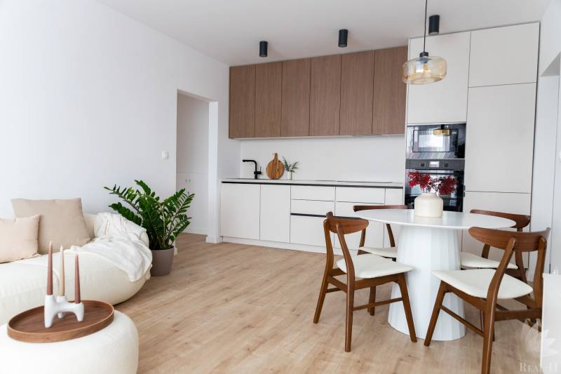 Nappali szoba konyhával egy háromszobás lakásban, fa dekoros padlóval.