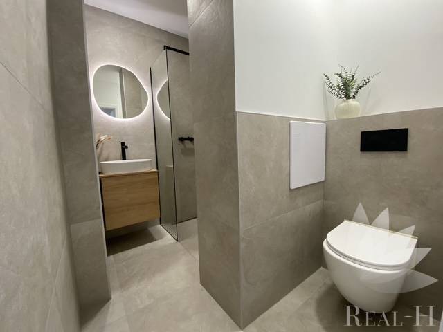 Fürdőszoba egy kétszobás lakásban WC-vel, mosdóval és tükörrel.