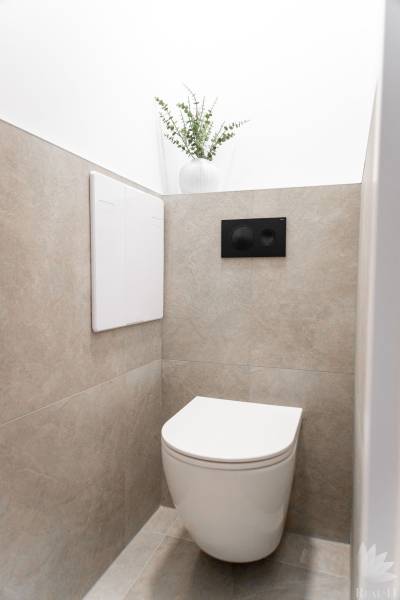 Függesztett WC-vel és dísznövénnyel ellátott WC egy háromszobás lakásban.