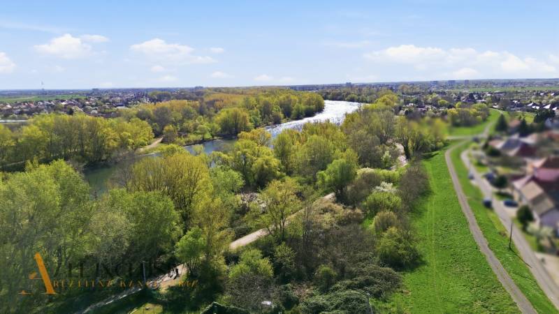 Kilátás a kertekre Vághosszúfalu (Királyfa) területén, a folyóval és gazdag zöld növényzettel.