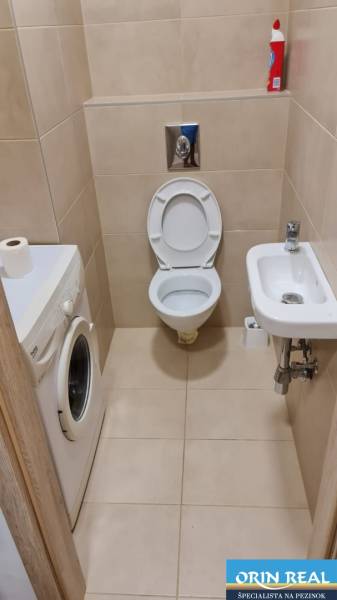 Fürdőszoba garzonlakásban WC-vel, mosógéppel és kis mosdókagylóval.