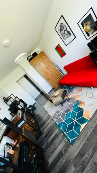 Nappali egy háromszobás lakásban, piros kanapéval és fa dekoros padlóval.