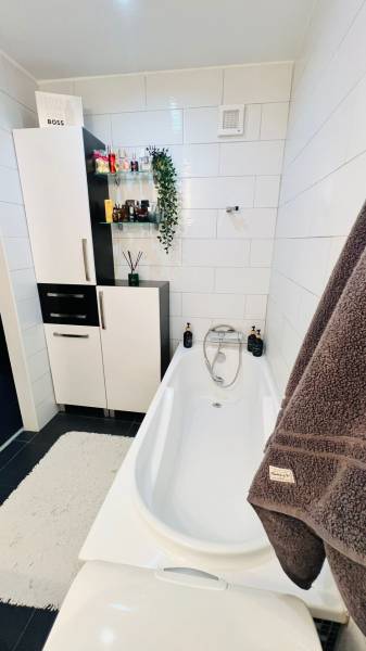 Fürdőszoba káddal, szekrényekkel és dekorációkkal egy háromszobás lakásban.